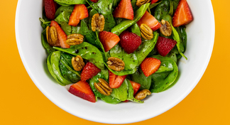 A white bowl of strawberry spinach salad