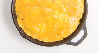 An iron skillet filled with Shepherd&#039;s Pie; a recipe using ground beef, green beans, mashed potatoes, and cheese.