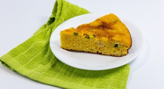 A white plate with a wedge of Fiesta Cornbread on a green napkin