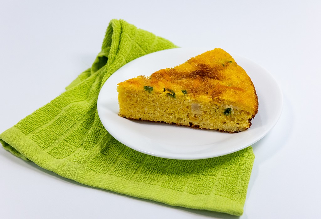 A white plate with a wedge of Fiesta Cornbread on a green napkin