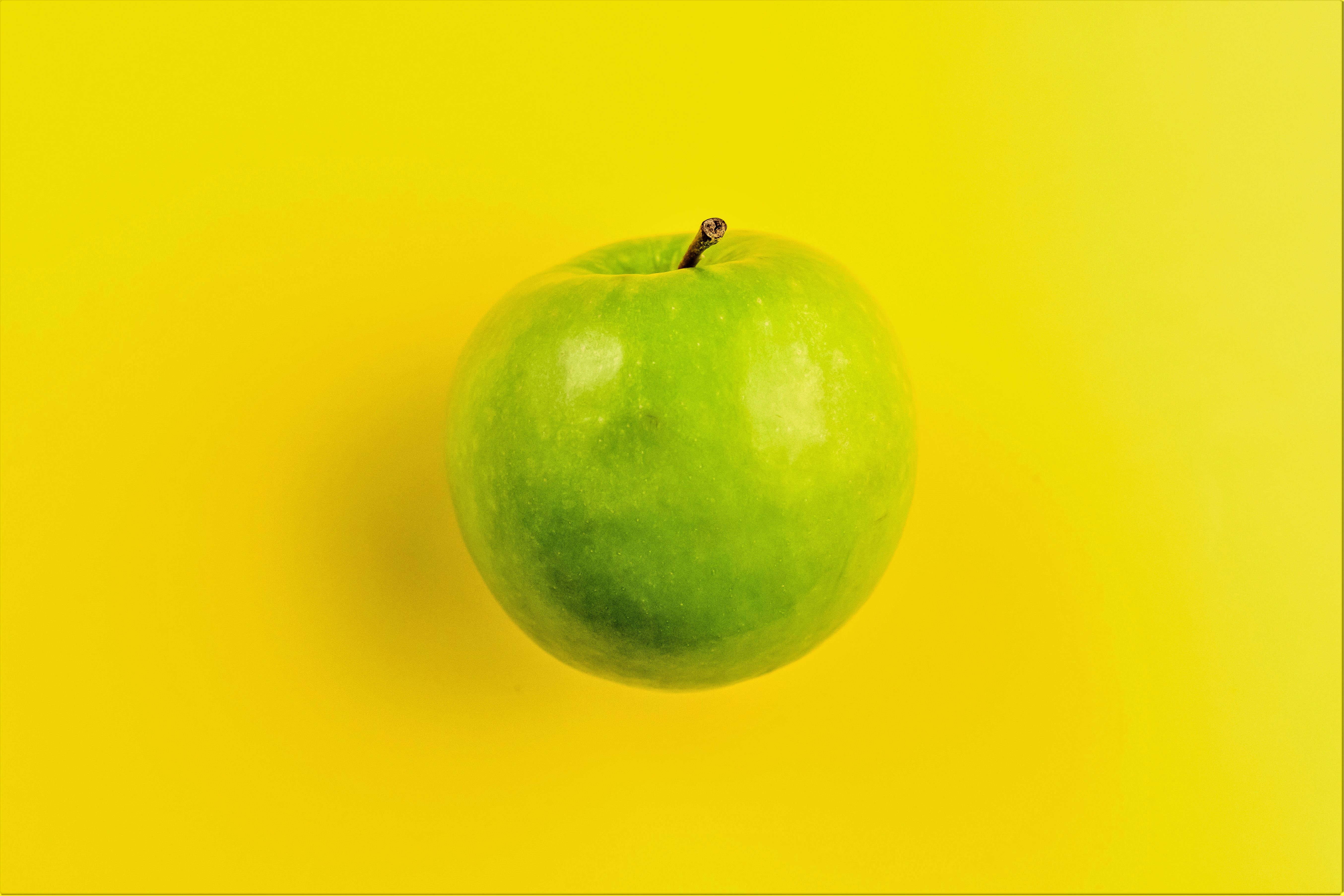 A green apple on a yellow background
