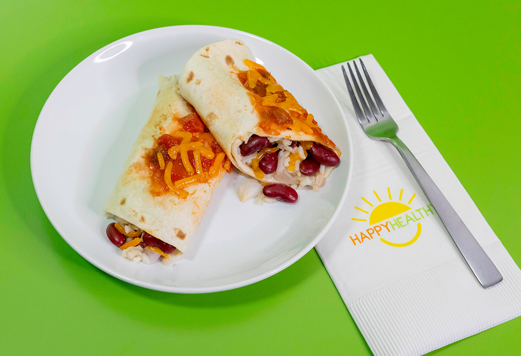 A plate with a bean and rice burrito next to a napkin and fork on a green background