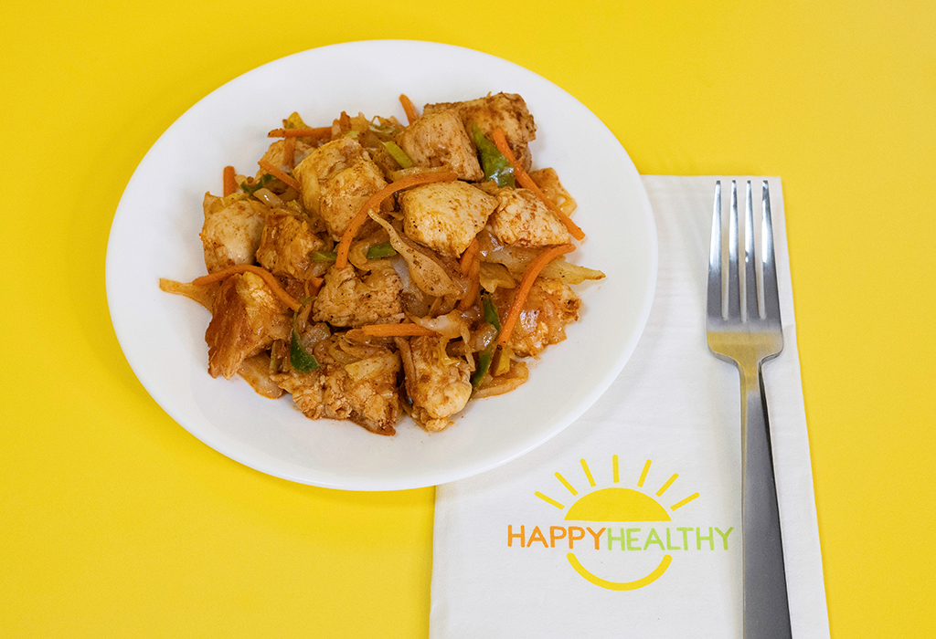 a white plate filled with cabbage and chicken on a yellow background next to a napkin and fork