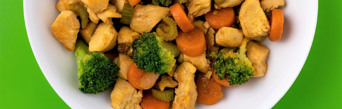 Chicken stir fry dish with sauteed carrots, broccoli, celery and chicken in a white bow