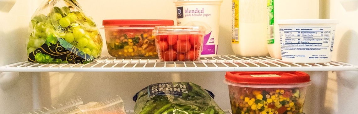 various fruits and vegetables in plastic bags and containers on refrigerator shelves