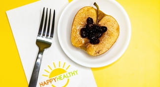 Microwaved apple half on a white plate with raisins on top. HappyHealthy napkin and fork to left of plate.
