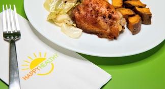 Blackened chicken with roasted vegetables on white plate with HappyHealthy napkin and fork to the side.