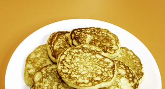 A white plate filled with pancakes on an orange background