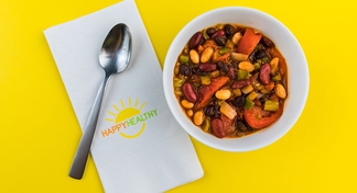 3 Bean Chili in a bowl with a spoon on a HappyHealthy napkin.
