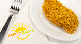 A baked flaked chicken breast on a white plate next to HappyHealthy napkin and fork
