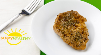 Baked Pork Chop on white plate next to white HappyHealthy napkin and fork