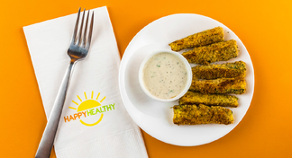 Plate with zucchini sticks and cup of low-fat ranch dressing beside a napkin and fork.
