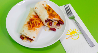 A plate with a bean and rice burrito next to a napkin and fork on a green background