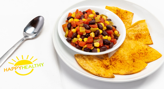 Black Bean and Corn Salsa in white bowl on white plate with chips, next to HappyHealthy napkin and spoon