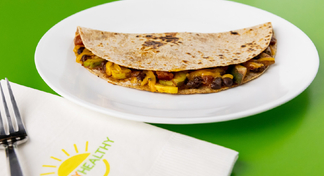 Black Bean & Vegetable Quesadilla on white plate next to HappyHealthy napkin and fork