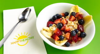Breakfast Banana Split in white bowl next to HappyHealthy napkin and spoon.