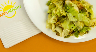 A plate filled with a serving of cabbage stir-fry with a HappyHealthy napkin to the side.