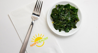 Plate of collard greens beside napkin and fork.