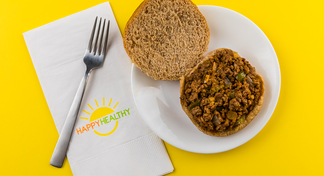 Easy Sloppy Joes (with bun) on a plate with a fork on a HappyHealthy napkin.
