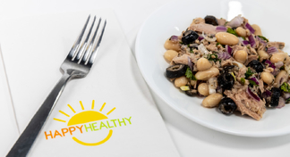 A plate of Greek style tuna salad next to fork and happy healthy napkin