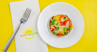 A single mini pizza on a white plate next to a Happy Healthy Napkin and Fork