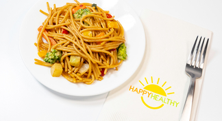 A white plate filled with Noodles and Peanut Sauce next to a fork and napkin