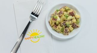 Plate with potato salad beside a napkin and fork. beside a napkin and fork.