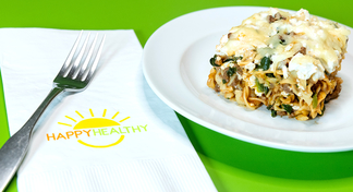 A fork and Happy Healthy napkin next to a white plate with a piece of quick lasagna on top