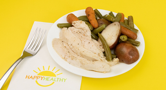 chicken with vegetables on a white plate next to a HappyHealthy napkin and fork