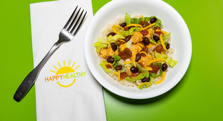 A southwest bowl with rice, chicken, lettuce, black beans, salsa, cheese next to a fork and HappyHealthy napkin