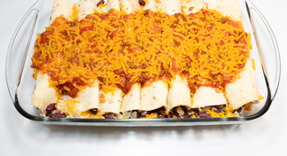 A glass casserole pan of bean and Rice burritos on a white background