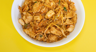 a white bowl filled with cabbage and chicken on a yellow background