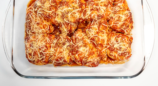 A casserole dish filled with chicken parmesan on a white background