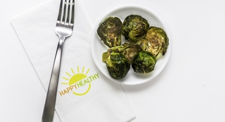 Bowl of roasted brussels sprouts beside napkin and fork